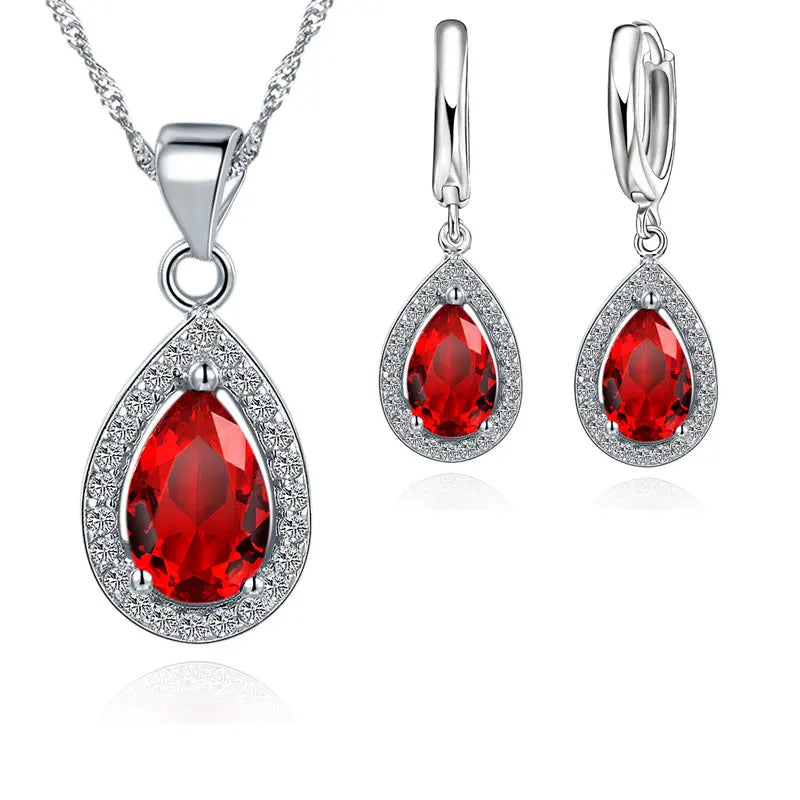 Jewelry set with red teardrop-shaped gemstones on a white background