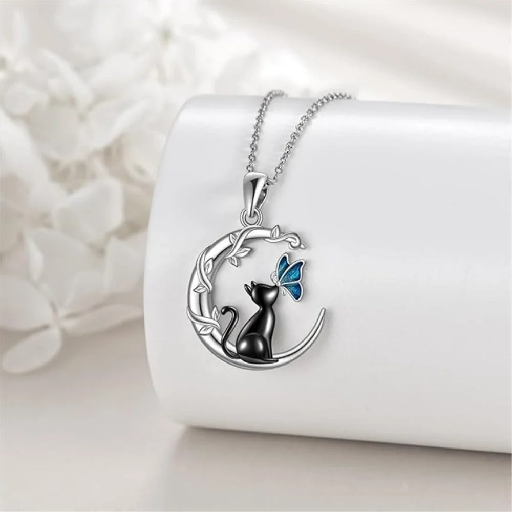 Silver necklace with a cat and butterfly pendant on a white surface