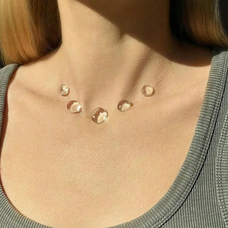 Necklace with clear pendant on a person wearing a green top