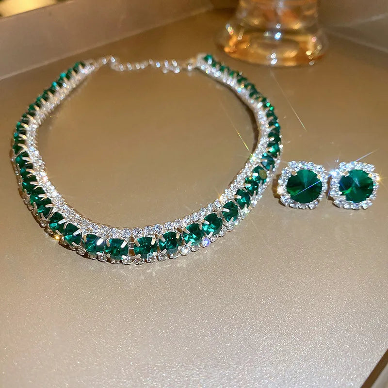 Green and silver necklace and earrings on a reflective surface