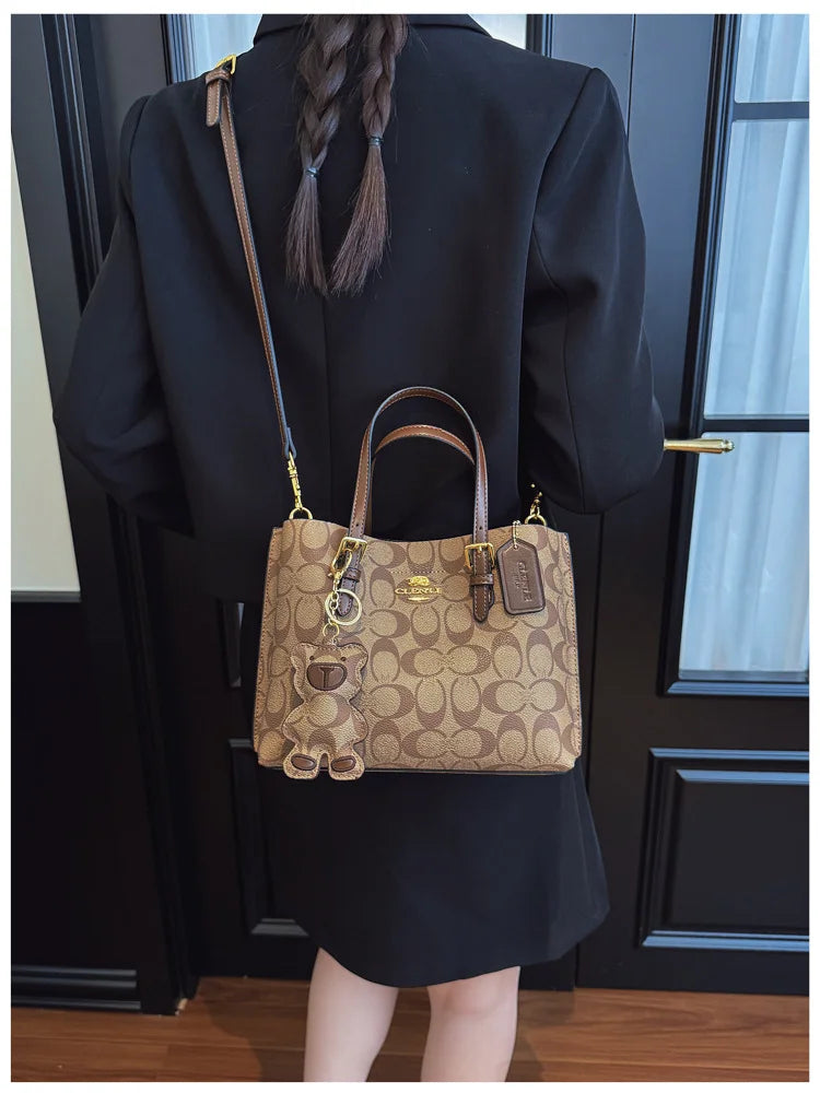Person wearing a black outfit with a brown Coach handbag.