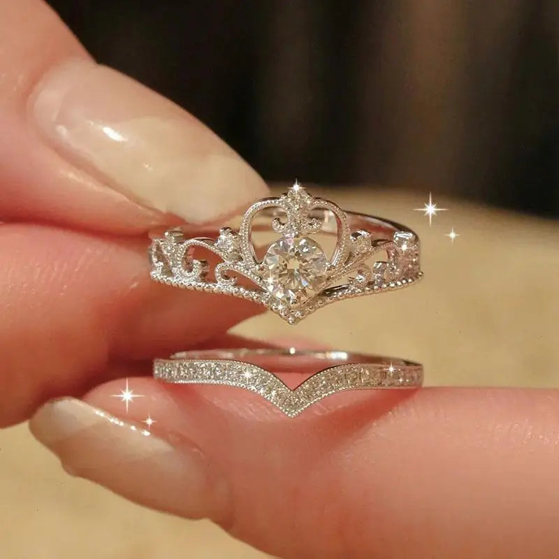 Two silver rings with intricate designs held between fingers against a blurred background