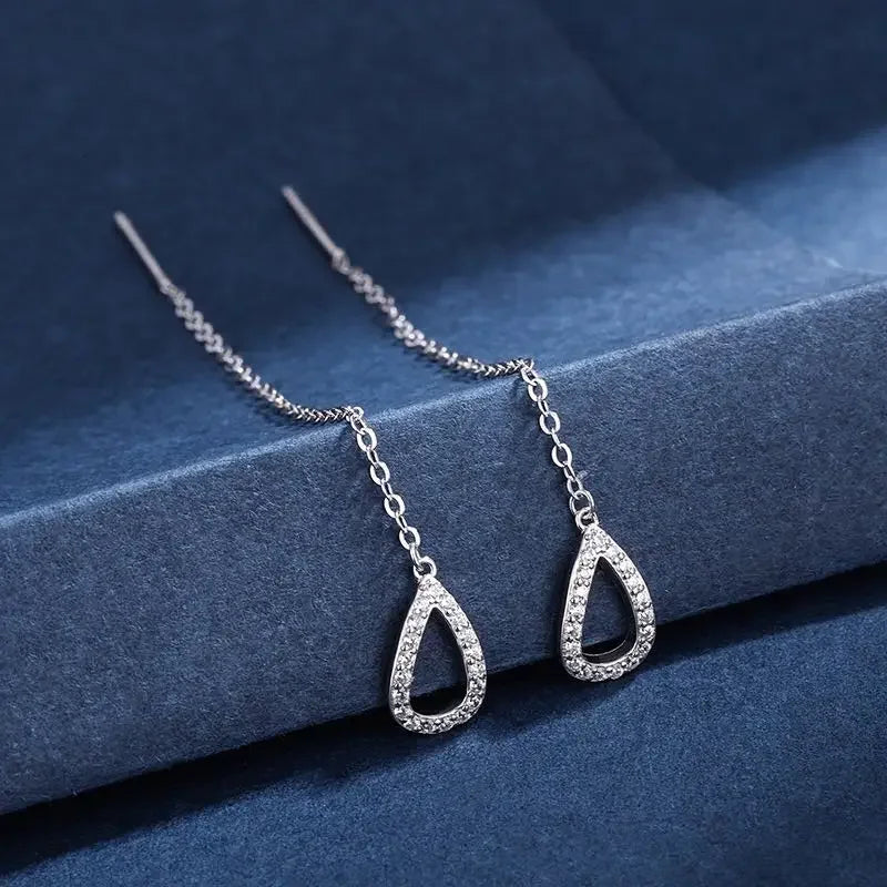 Silver teardrop earrings on a blue surface