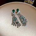 Pair of earrings with green gemstones on a beige surface