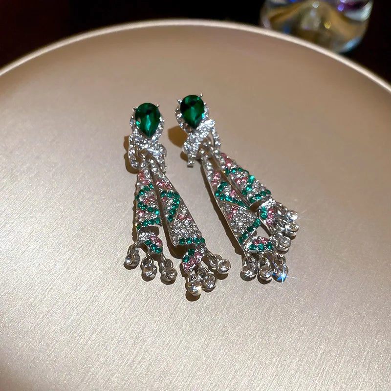 Pair of earrings with green gemstones on a beige surface