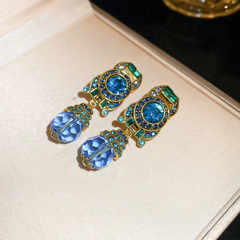 Ornate earrings with blue and green gemstones on a light background