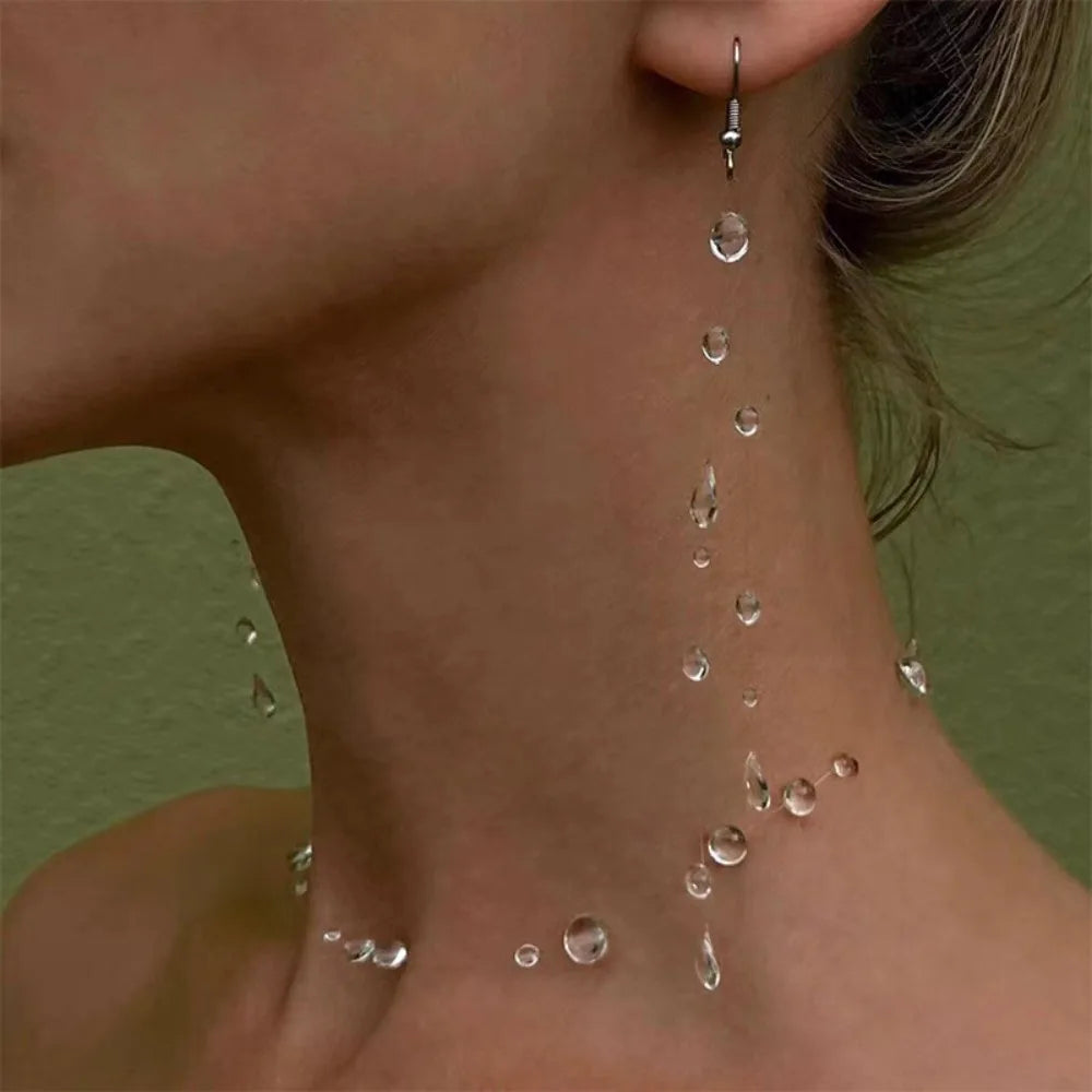 Close-up of a person's neck with water droplets and a dangling earring.