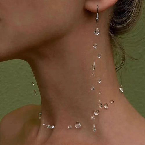 Close-up of a person's neck with water droplets and a dangling earring.