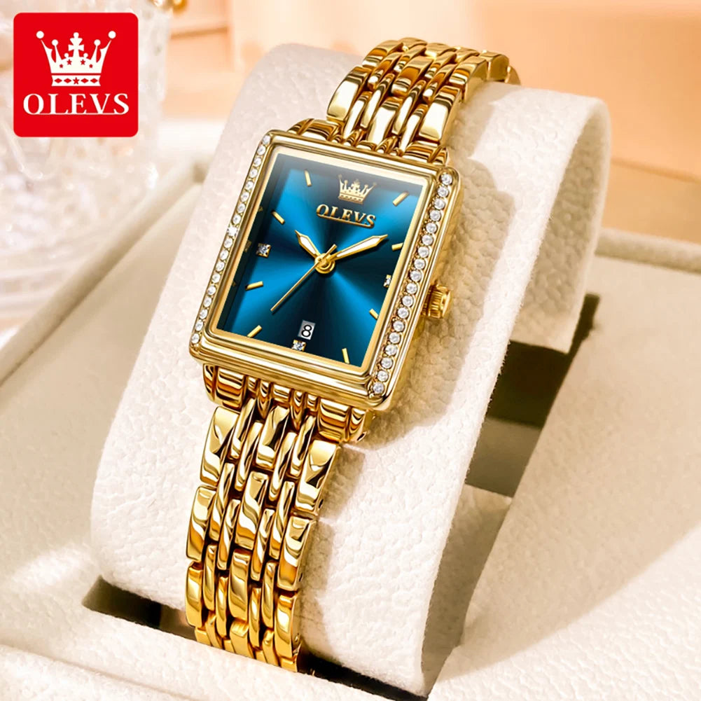 Gold wristwatch with blue face on a white stand, OLEVS brand visible