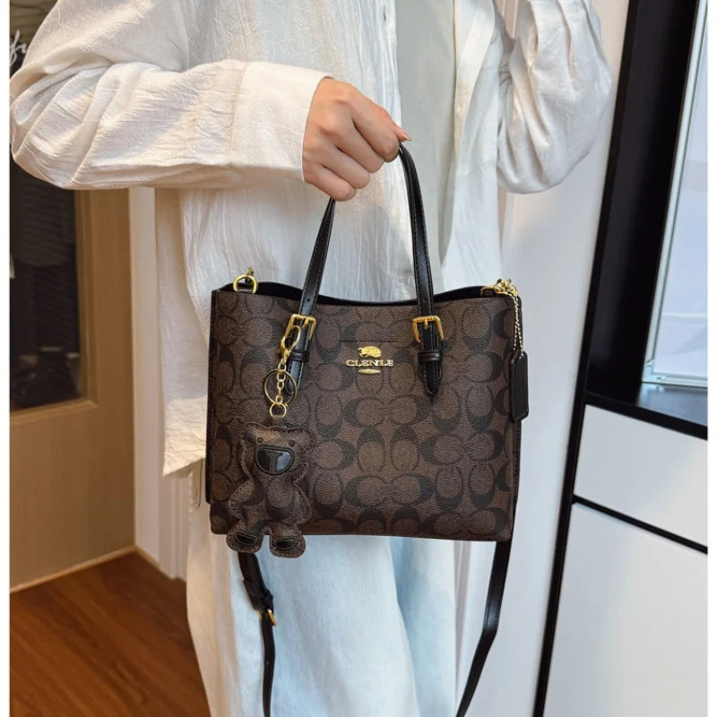 Person holding a Coach handbag with a patterned design.