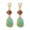 Pair of earrings with green teardrop stones and gold accents on a white background