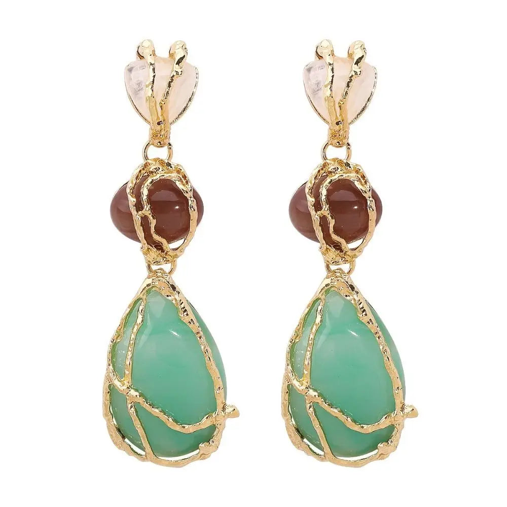 Pair of earrings with green teardrop stones and gold accents on a white background