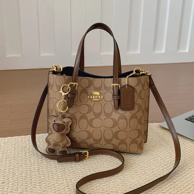 Coach handbag with teddy bear charm on a textured surface