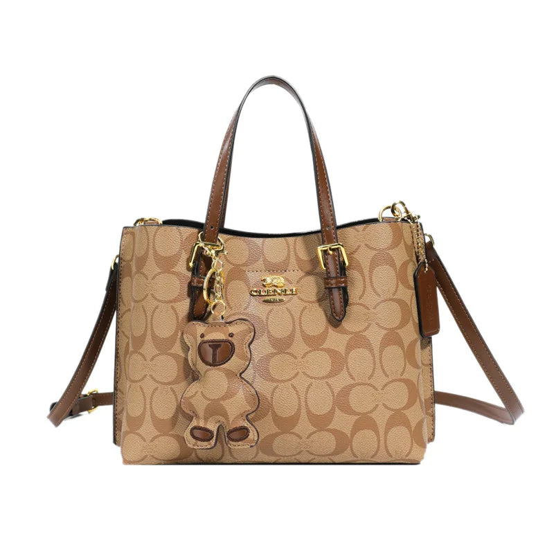 Beige handbag with brown accents and gold hardware on a white background