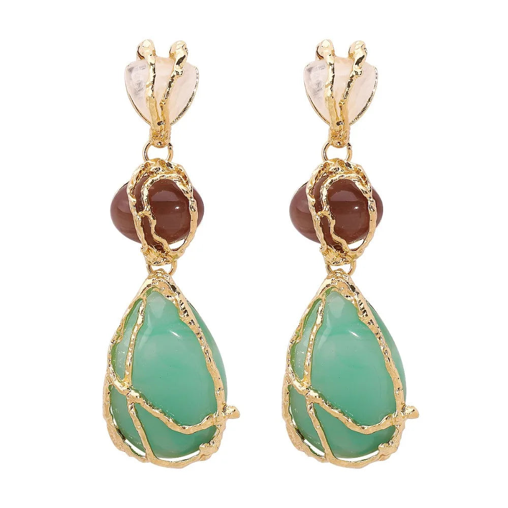 Pair of earrings with green teardrop stones and gold accents on a white background