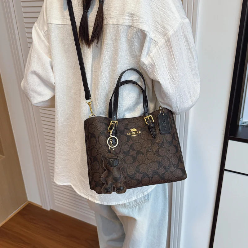 Brown Coach handbag worn over shoulder with a white outfit