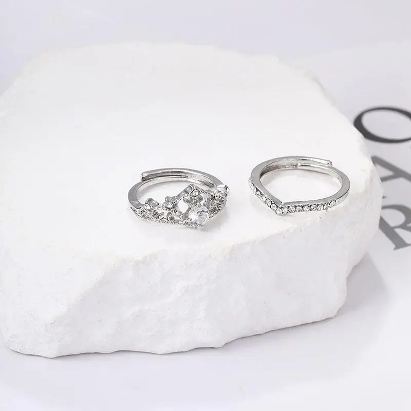 Two silver rings with gemstones on a white stone surface