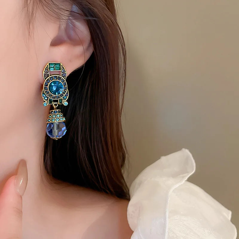 Close-up of a person wearing an ornate earring with gemstones.